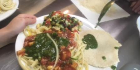 Yellow and green zucchini noodles topped with pesto and tomato sauce.